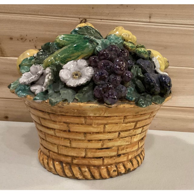 Beautiful vintage majolica basket filled with fruit, vegetables, and flowers surrounded by foliage.