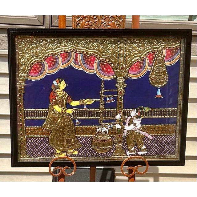 This Tanjore painting is truly a visual delight! Thin sheets of gold leaf have been pressed onto a wooden board, then...