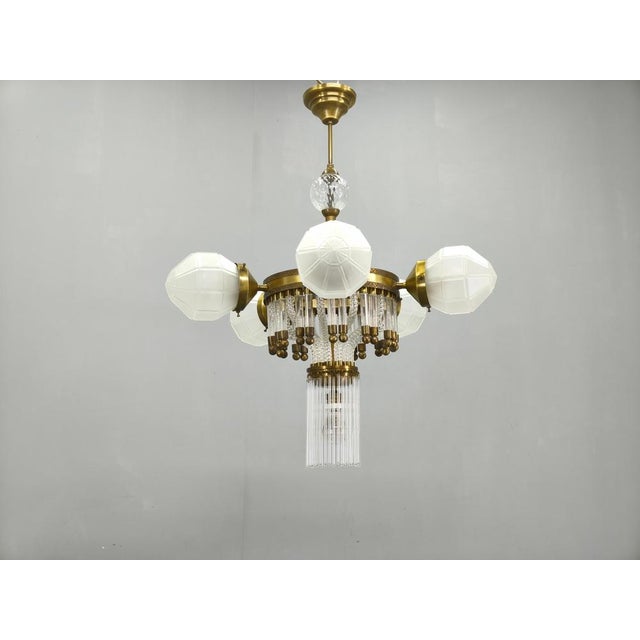 Elegant art deco-inspired chandelier produced in czechoslovakia during the 1950s. Crafted from brass and featuring a...