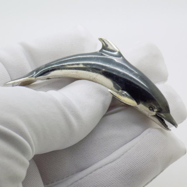 This vintage silver decorative object depicts a dolphin figurine, crafted as a vitrine centerpiece, desk sculpture, or...