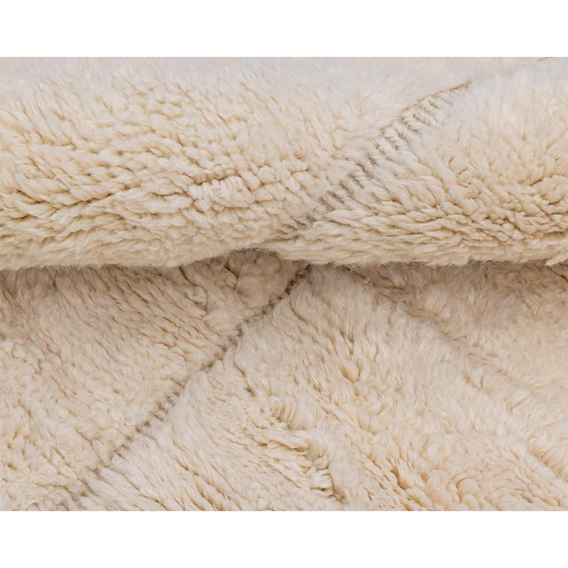 Minimalist hand-knotted wool rug, enriched with a subtle handwoven abstract grid pattern in a gentle Ivory palette,...