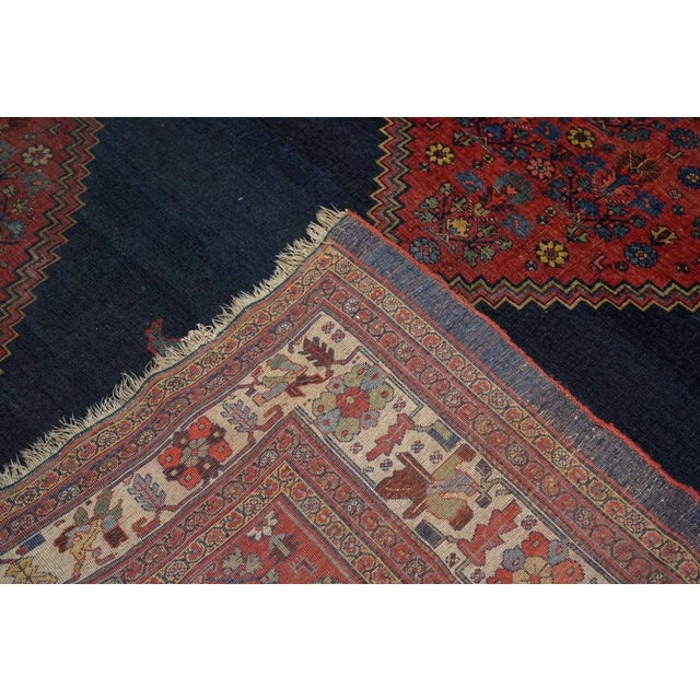 The open navy field shows off the red, stepped medallion with light blue pendants. A semi-geometric floral scatter...