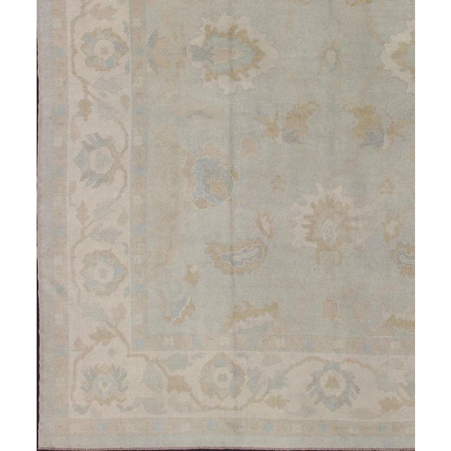 This vintage Turkish Oushak rug is remarkably elegant in both color and design. The central field of light gray plays host...
