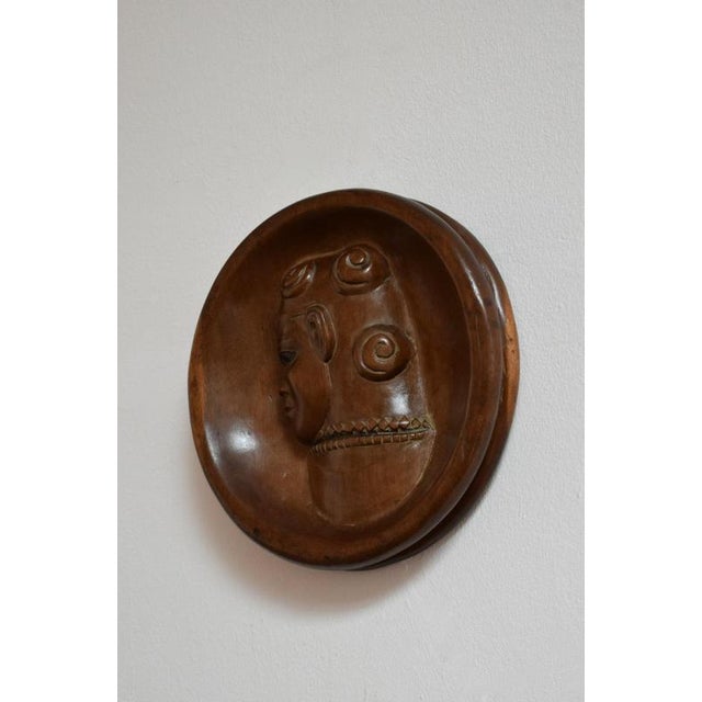 Africanist low relief round wooden wall sculpture, 1970s. Africanist tondo wall panel sculpture in carved wood with a...