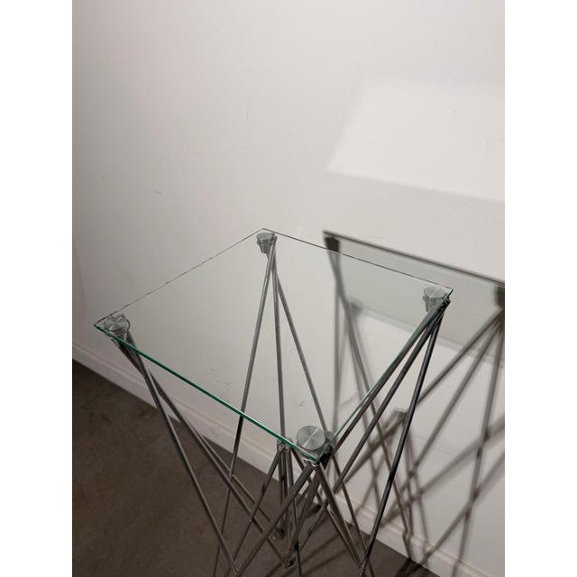 Distinctive Bjart folding pedestal table featuring an architectural metal rod construction and a clear glass top. The...