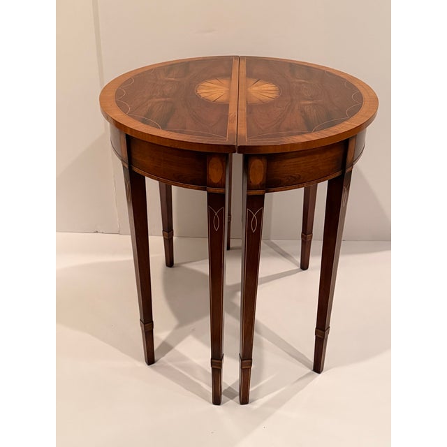 Classic pair of flame mahogany demilune consoles having beautiful inlay detail and fan decoration.