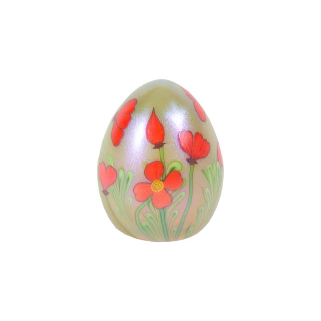 An iridescent art glass paperweight by Orient and Flume. This egg-shaped paperweight features vibrant poppy flowers...