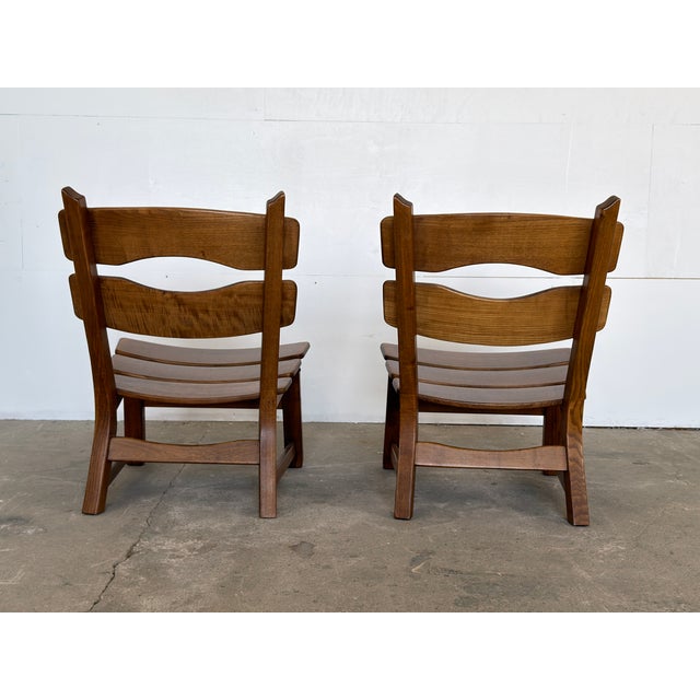 A pair of solid oak low lounge chairs by Dittmann & Co, Europe, 1960s. The defining feature is the double wave-cut back...