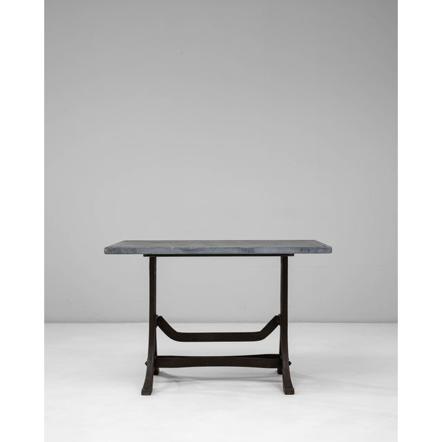 An authentic industrial table combining wrought iron framing with a durable stone top, reflecting workshop and factory...