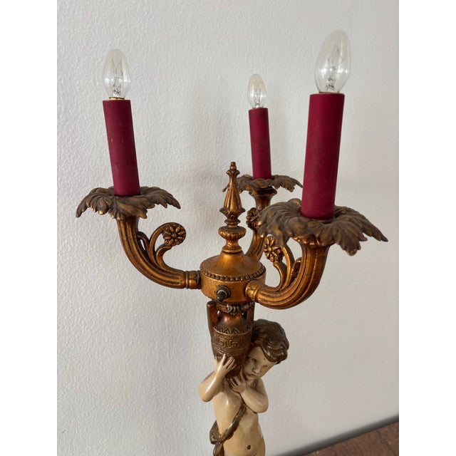 Antique Neoclassical figural candelabra table lamp, featuring a cherub or putti figurine holding a candelabra, set on a...