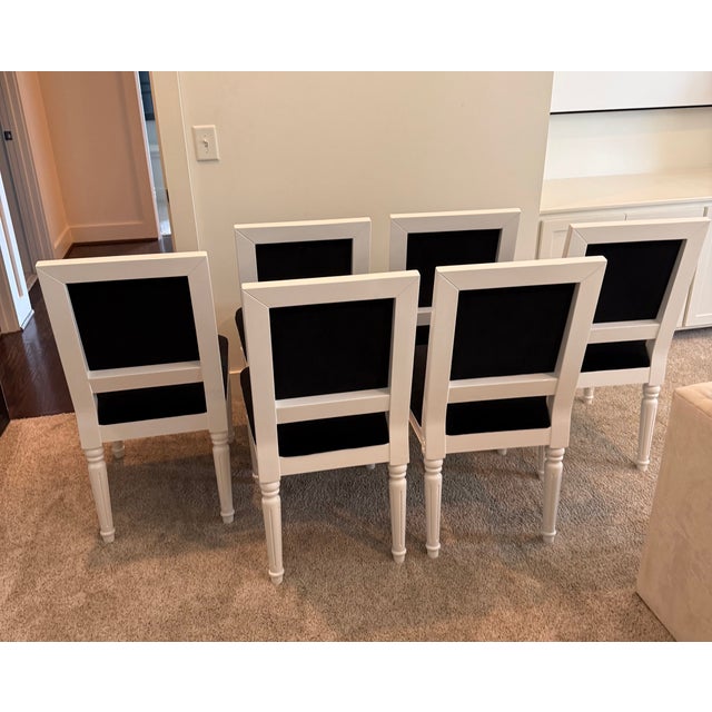 Modern white lacquered dining chairs with black velvet seats and backs. Floral medallions on the front corners and reeded...