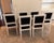 Modern white lacquered dining chairs with black velvet seats and backs. Floral medallions on the front corners and reeded...