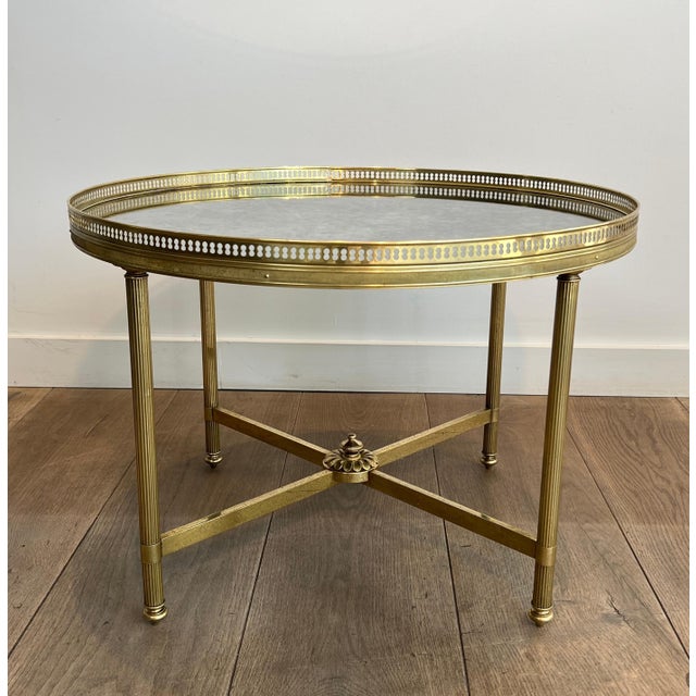 This magnificent neoclassical-style round coffee table is made of brass with faux-antique mirrors. It is a French work by...