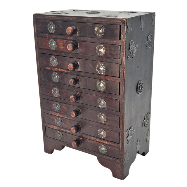 A compact hardwood cabinet in the Anglo-Indian decorative tradition featuring eight narrow drawers arranged in a classic...