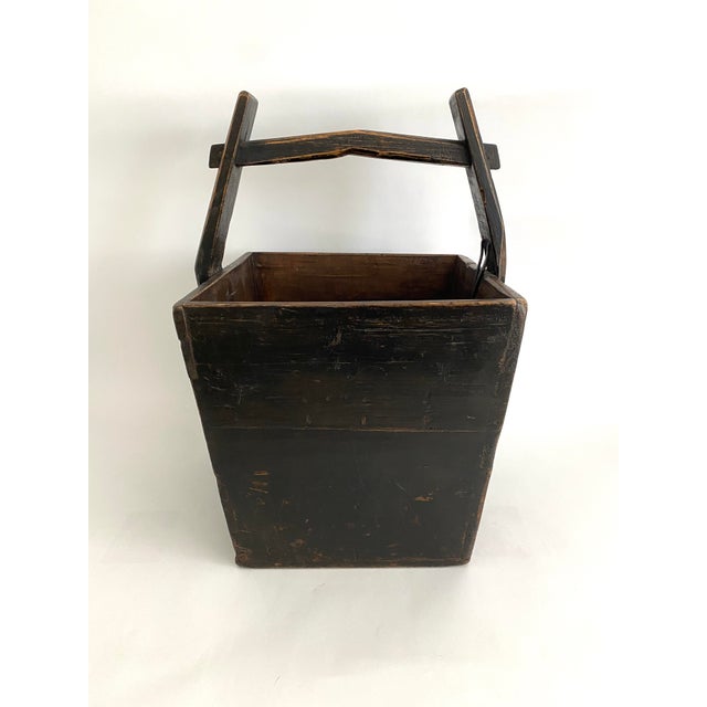 This antique Chinese wooden box was used for transporting water. Painted black in perhaps it's original use, primitively...