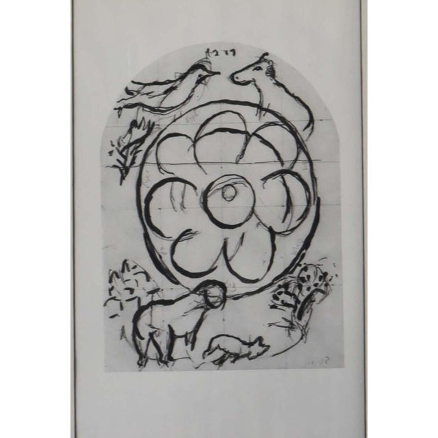 This is a black and white lithograph print featuring a central, stylized floral or wheel-like motif. Surrounding the...