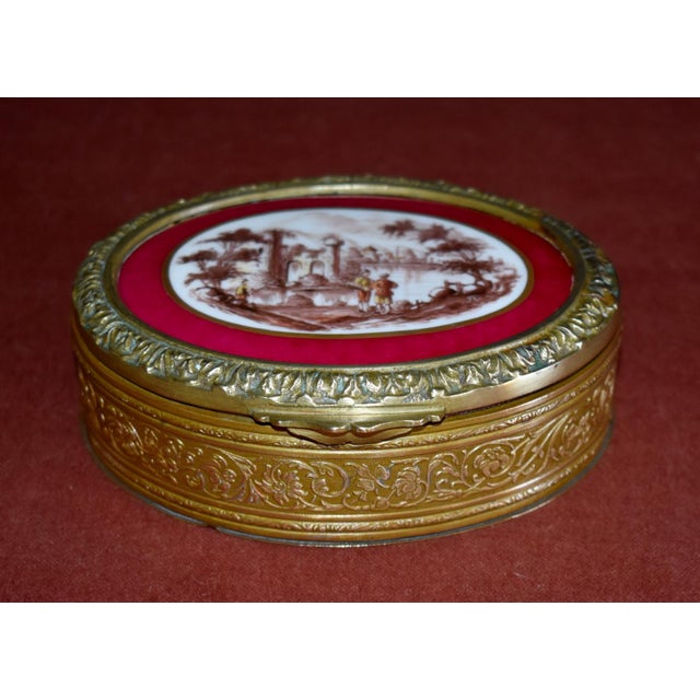 Antique - Late 19th Century Jewelry Box is French. Made of Brass with a Painted Porcelain Vignette/Ruby Enamel. The...