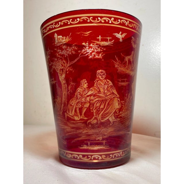 Experience the elegance of the Victorian era with this exquisite 1865 Bohemian cranberry glass bucket vase. The rich...