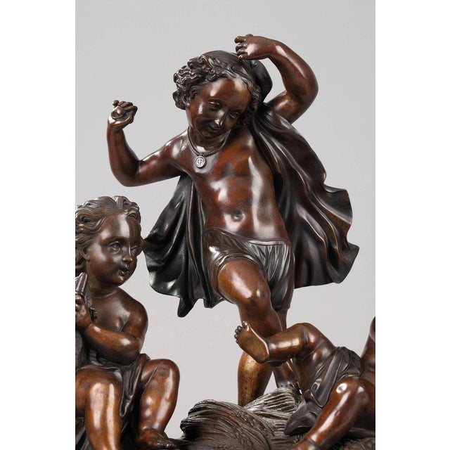 Patinated bronze allegorical group featuring three putti on a cliff strewed with wheat. Two of them are playing the drum...