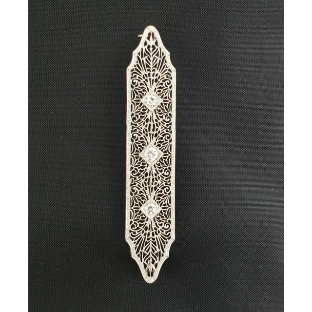 This lovely Art Deco brooch is crafted from platinum and has 14k white gold pin. The long frame has fine filigree floral...