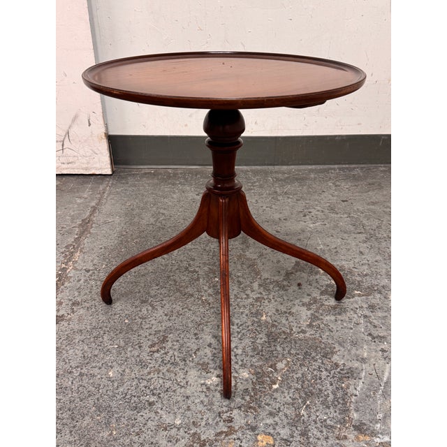 Design Plus Gallery presents a Vintage Georgian Style Mahogany Side Table. The round top is detailed with a raised lipped...