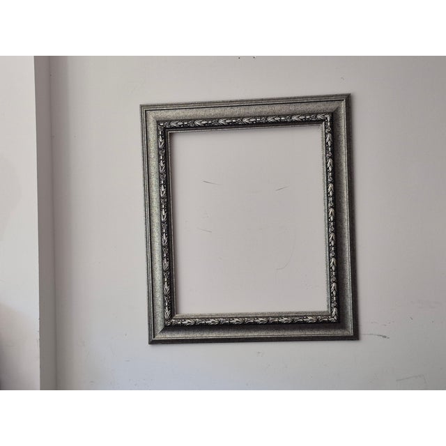 3.75" wide wood frame, not attached to painting, ( but painting fits). Raised, elegant embossing on silver and black wood...
