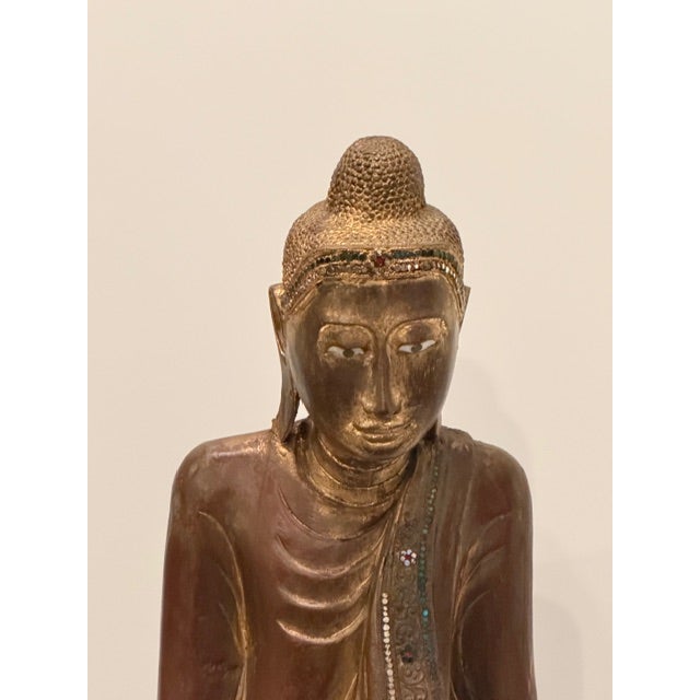 Strikingly large carved and gilded standing Buddha having intricate detail and inlaid with colored glass.