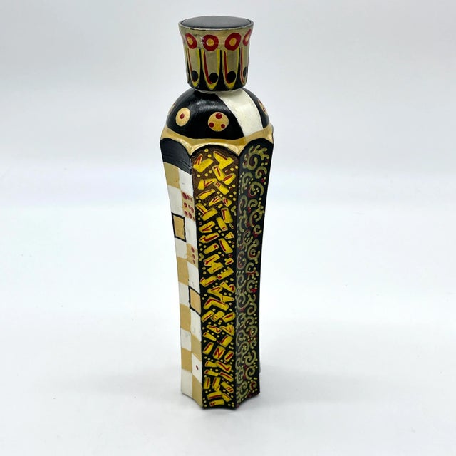This glass bottle has been hand-painted with black and white checkerboards, polka dots, and whimsical artistic accents....