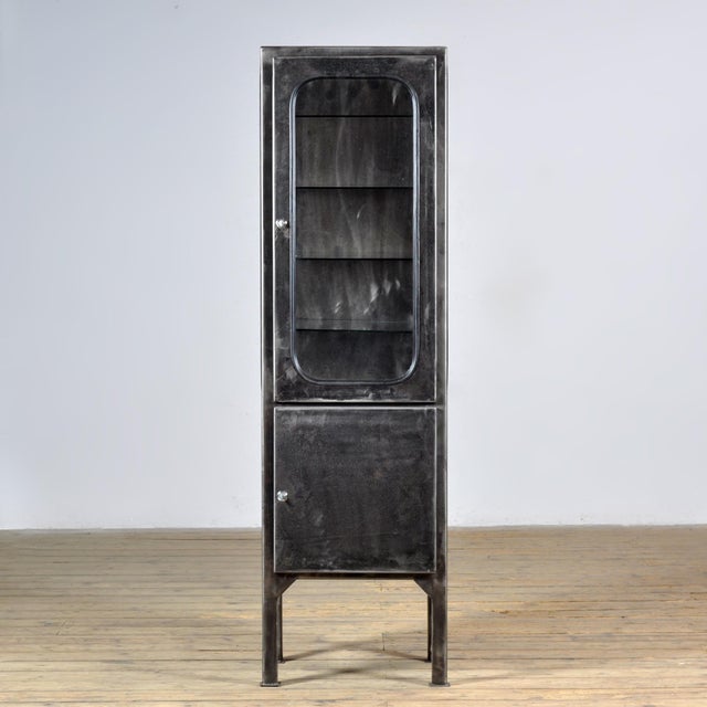 Vintage medicine cabinet from the 1970s, produced in Hungary. The cabinet is made of iron and glass, with the glass held...