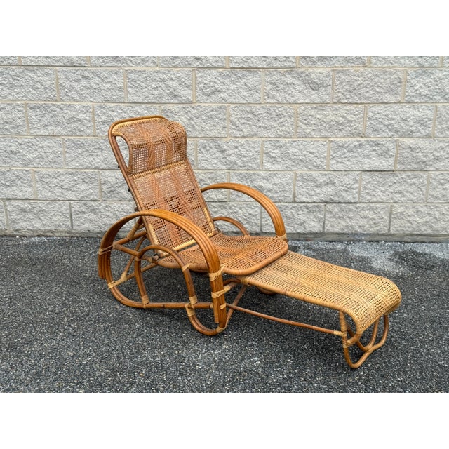 Unusual vintage rattan lounge chair featuring a reclining back and an ingenious integrated pull-out ottoman. The footrest...