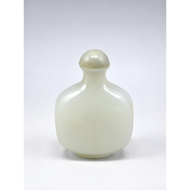 A finely carved Chinese white jade snuff bottle, distinguished by its beautifully understated form and soft, luminous...