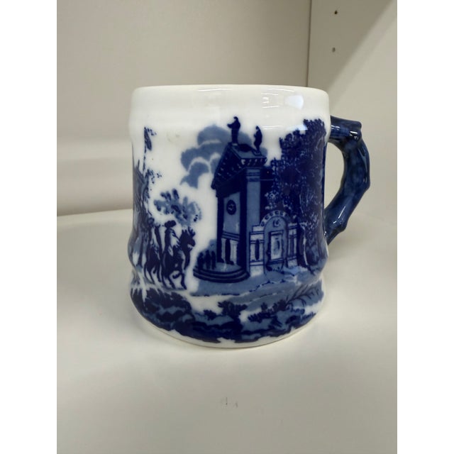 A charming vintage blue and white transferware mug featuring wraparound pastoral landscapes, quaint village scenes, and...