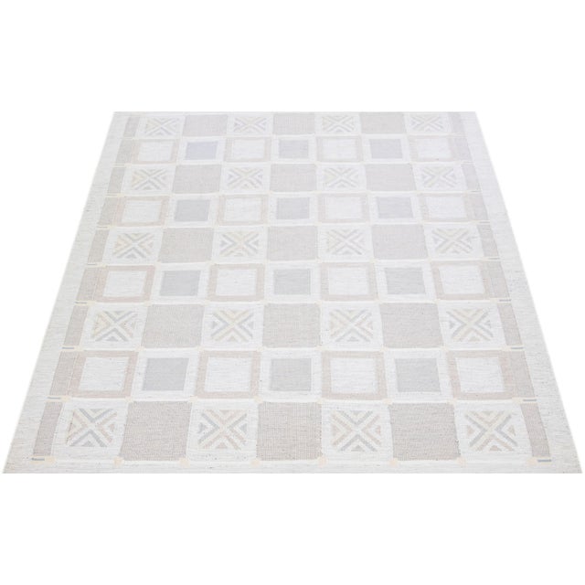 This modern Swedish flat weave rug presents a striking balance of cool and warm tones within a timeless geometric...
