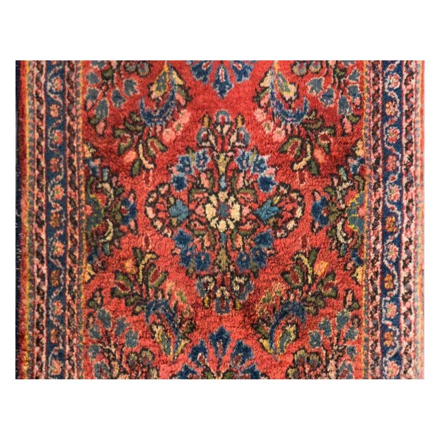 A petite early 20th century Persian Sarouk rug with a floral pattern woven in light and dark indigo, green, pink, and...