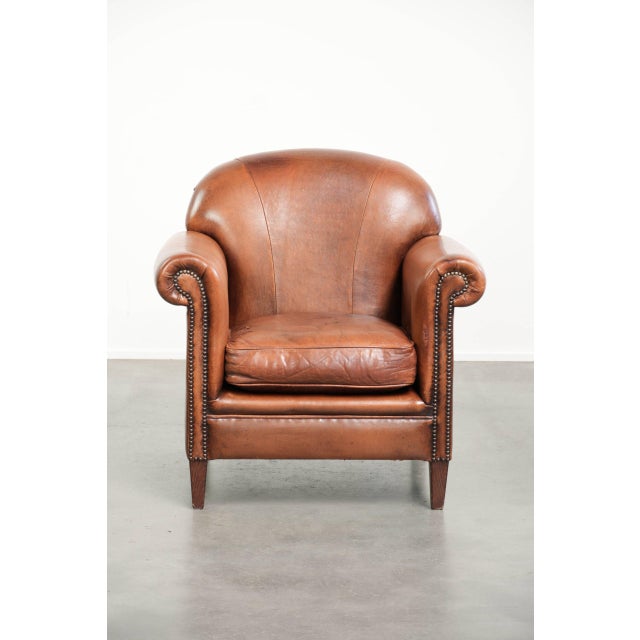 This comfortable vintage sheepskin armchair finished with decorative nails. This vintage sheepskin armchair has a...