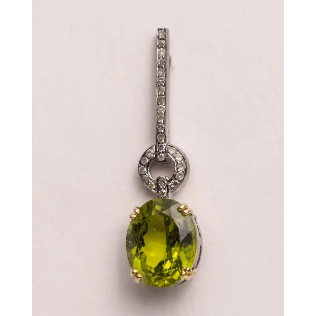 A lovely pair of drop earrings with large, faceted oval peridot gemstones with round, brilliant cut diamonds in a pave`...