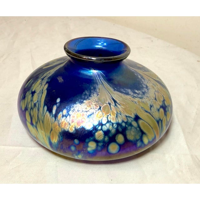 The vintage hand blown Kent Fiske blue iridescent vase is a unique and artistic piece of glassware. Made in 1982, this...