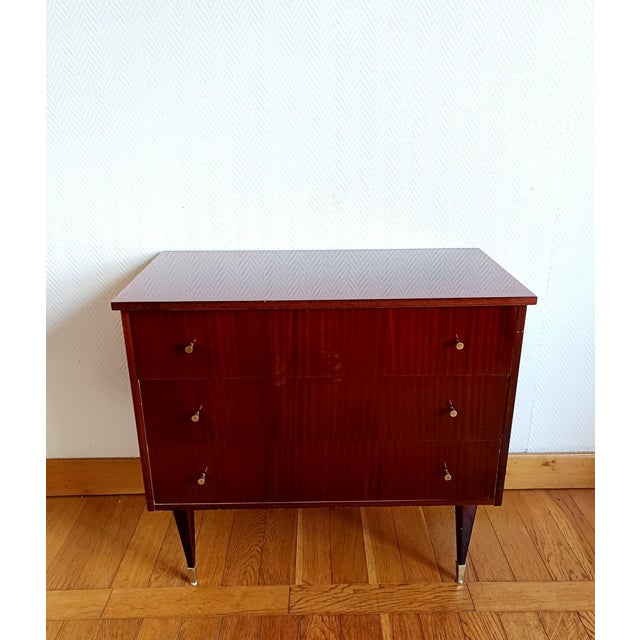 Vintage 1950s dark lacquered wood chest of drawers that opens into a dressing table. Features gold door knobs and gold-...