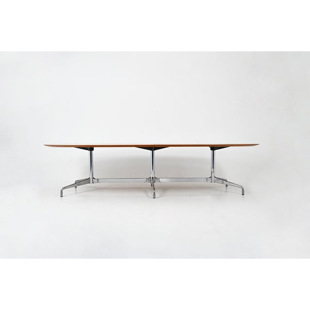 Large wooden table with metal base by Charles & Ray Eames. Wear consistent with age and time. This piece is attributed to...