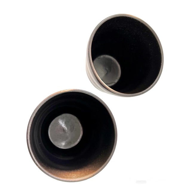 A pair of traditional Japanese ceramic tea cups. A chocolate brown with brush strokes in lighter shades of beige Stack for...