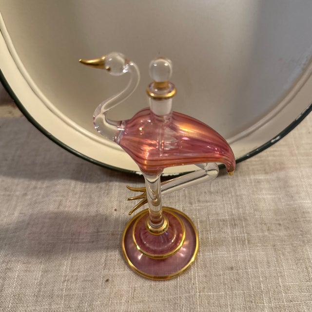 Vintage flamingo pink, clear, gold colored glass perfume bottle with glass stopper. Measures 5.25” high. Lovely piece.