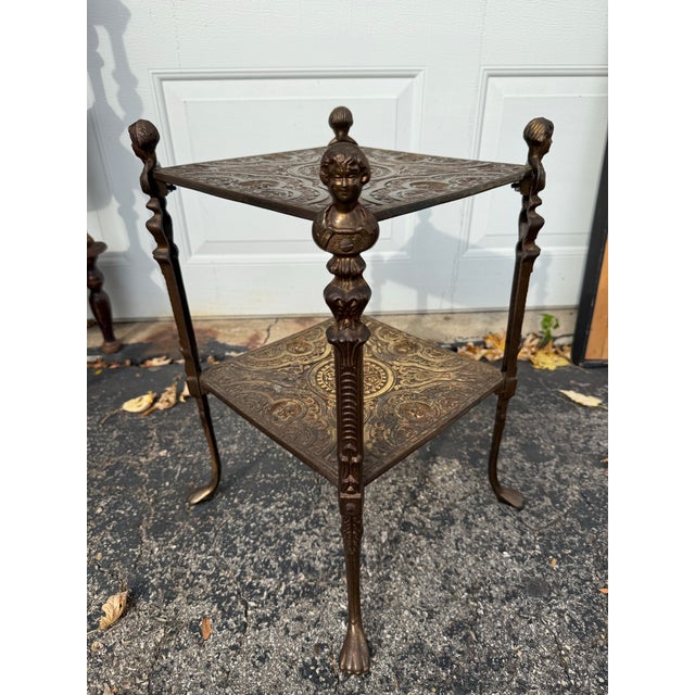 Extraordinary vintage two-tiered brass stand. Wonderful vintage patina. There is a female bust at the top of each of the...