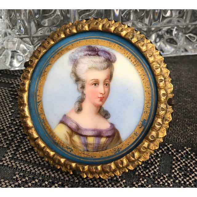 This very unique small hand painted French Woman's portrait. The painting is on a porcelain disk with hand painted gold...