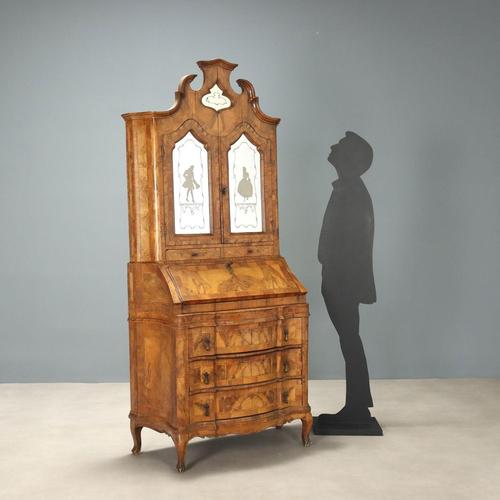 A late Baroque-style walnut veneered trumeau. Curved front sides, a three-drawer base with a drop-down door concealing an...