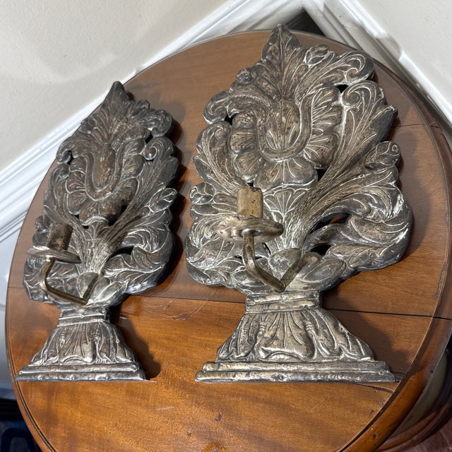 A pair of ornate vintage silver-tone metal wall candle sconces featuring elaborate repoussé style acanthus leaf and floral...