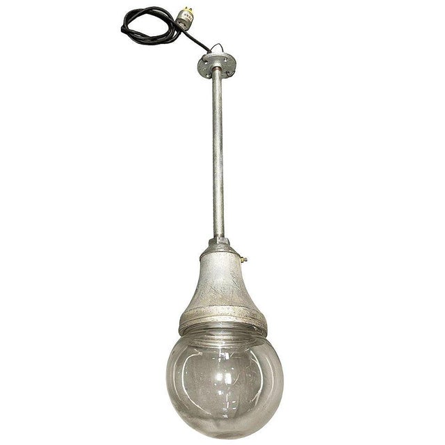 Pair of Benjamin Vapor-Tight industrial pendant lights featuring aluminum housings with original clear glass globe shade....