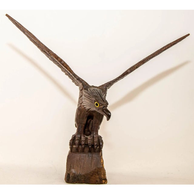 A large hand-carved iron wood eagle perched on a tree stump and surveying the surroundings ready to fly. Hand carved wood...