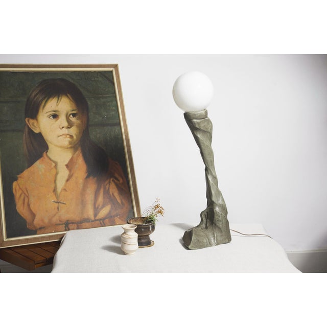 Vintage sculptural table lamp with a tall carved free-form tree trunk wood base, with a white opal glass globe. One...
