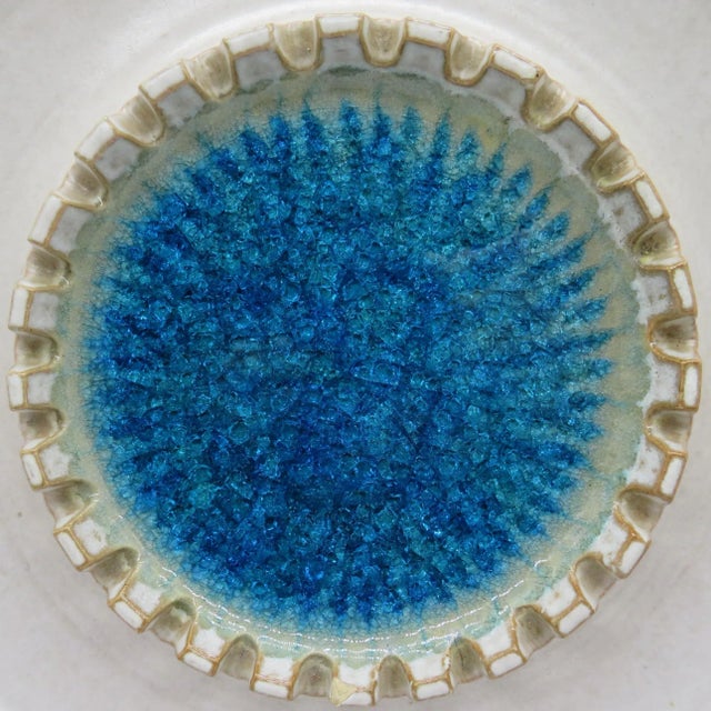 A mid-20th century slip-cast ecru ceramic ashtray filled with crushed glass, created by American ceramic artist Robert...