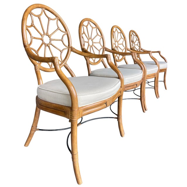 A stylish set of four rattan dining armchairs featuring distinctive circular medallion backs with radiating spoke detail...